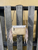 This cowhide and Beige leather bag features fringe sides and can be used as a wristlet or crossbody. It has a geometric print debossed flap with a whipstitch border.  Rear view showing zippered pocket. 