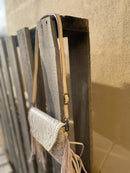 This cowhide and Beige leather bag features fringe sides and can be used as a wristlet or crossbody. It has a geometric print debossed flap with a whipstitch border.  Side view showing shoulder strap. 