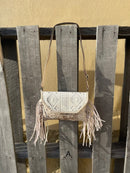 This cowhide and Beige leather bag features fringe sides and can be used as a wristlet or crossbody. It has a geometric print debossed flap with a whipstitch border.  Front View A