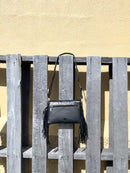 This cowhide and black leather crossbody bag has fringe sides. It features a whipstitch flap closure with a geometric design. Rear view showing back zippered closed pocket. 