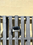 This cowhide and black leather crossbody bag has fringe sides. It features a whipstitch flap closure with a geometric design. Front View C