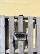 This cowhide and black leather crossbody bag has fringe sides. It features a whipstitch flap closure with a geometric design. Front View D