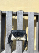 This cowhide and black leather crossbody bag has fringe sides. It features a whipstitch flap closure with a geometric design. Front View H