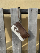 Cowhide wristlet purse in a Coffee Brown solid leather back and a zippered closure. It has a wristlet strap and a removable adjustable shoulder strap. Front View B