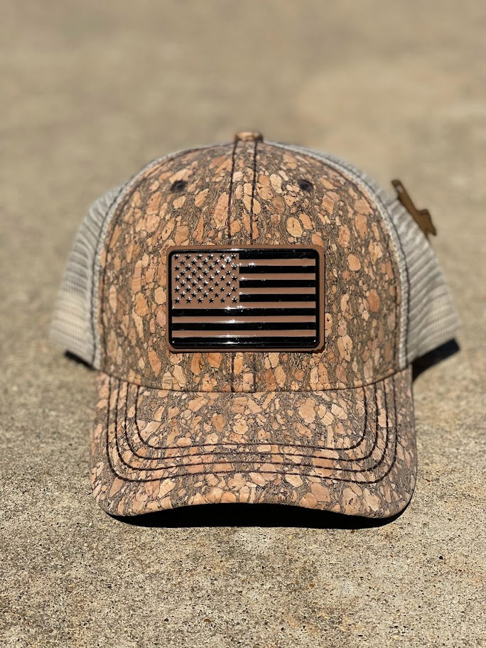 A brown cork cap with an metal  American flag Concho on the front, featuring an adjustable fit mesh back. Front View