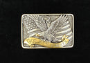 A rectangular, two-toned silver and gold belt buckle featuring an American flag and a bald eagle with the phrase 'God Bless America' written in a scroll ribbon.