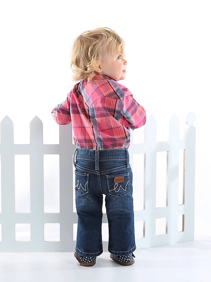 Toddler girl wearing Wrangler blue jeans with a brand logo on the back pockets. Back view.