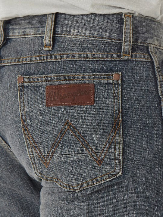 Closeup of back right pocket showing "W" sttitching, the neolite logo patch, and copper rivets on the top corners on a man wearing Wrangler Retro slim fit straight leg jeans with a dark night wash. 