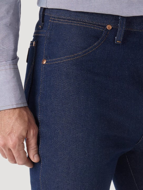 Closeup of front right scoop pocket of a man wearing Wrangler® Cowboy Cut®  slim fit rigid blue jeans with western shirt. Pocket has copper rivets on top corners and a coin pocket.