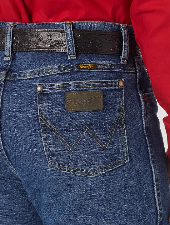 A close-up view of the back pocket of a Wrangler men's George Strait Cowboy Cut slim fit jeans showing the top rivets, faux leather logo patch, and the "W" stitching.