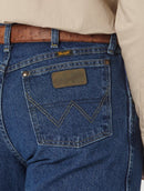 A close-up view of the back pocket of a Wrangler men's George Strait Cowboy Cut relaxed fit jeans showing the top rivets, faux leather logo patch, and the "W" stitching.