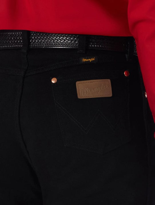 Closeup of back right back pocket of a man wearing Wrangler men's shadow black prewashed cowboy cut original fit jeans with western shirt and belt. Pocket has copper rivets on top corners  and neolite brown logo patch.