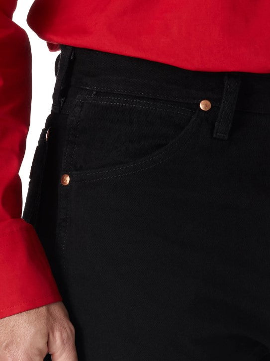 Closeup of front right scoop pocket of a man wearing Wrangler men's shadow black prewashed cowboy cut original fit jeans with western shirt. Pocket has copper rivets on top corners and a coin pocket.