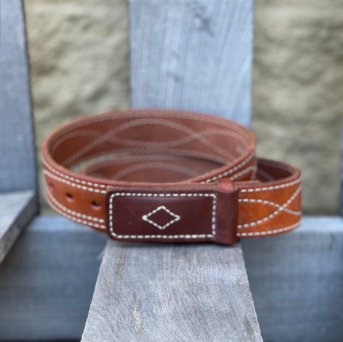 A brown leather work belt with white figure 8 stitching, leather buckle with prong closure. Front view.