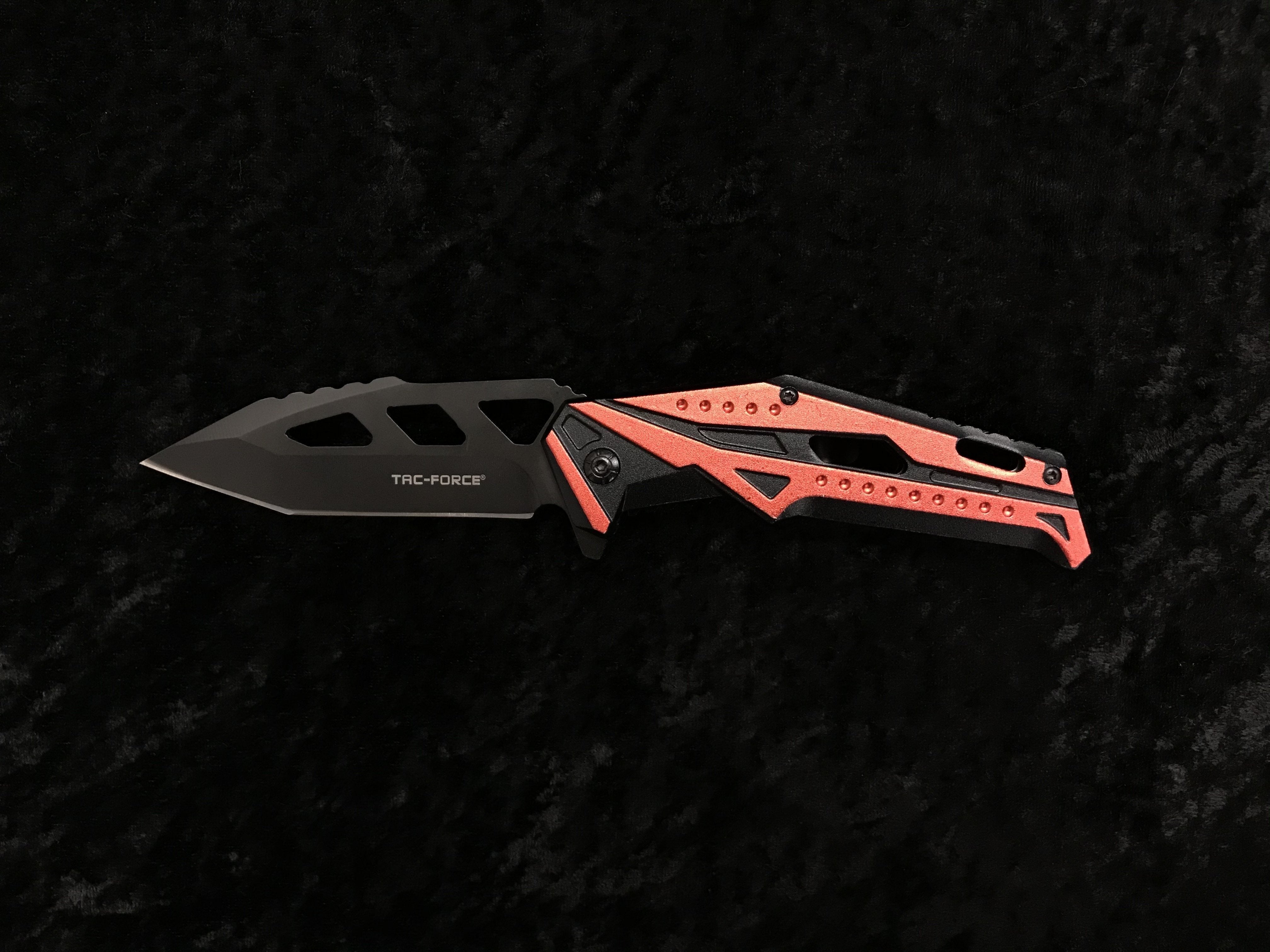 A black and red Tac-Force folding knife with a spring-assisted opening mechanism.