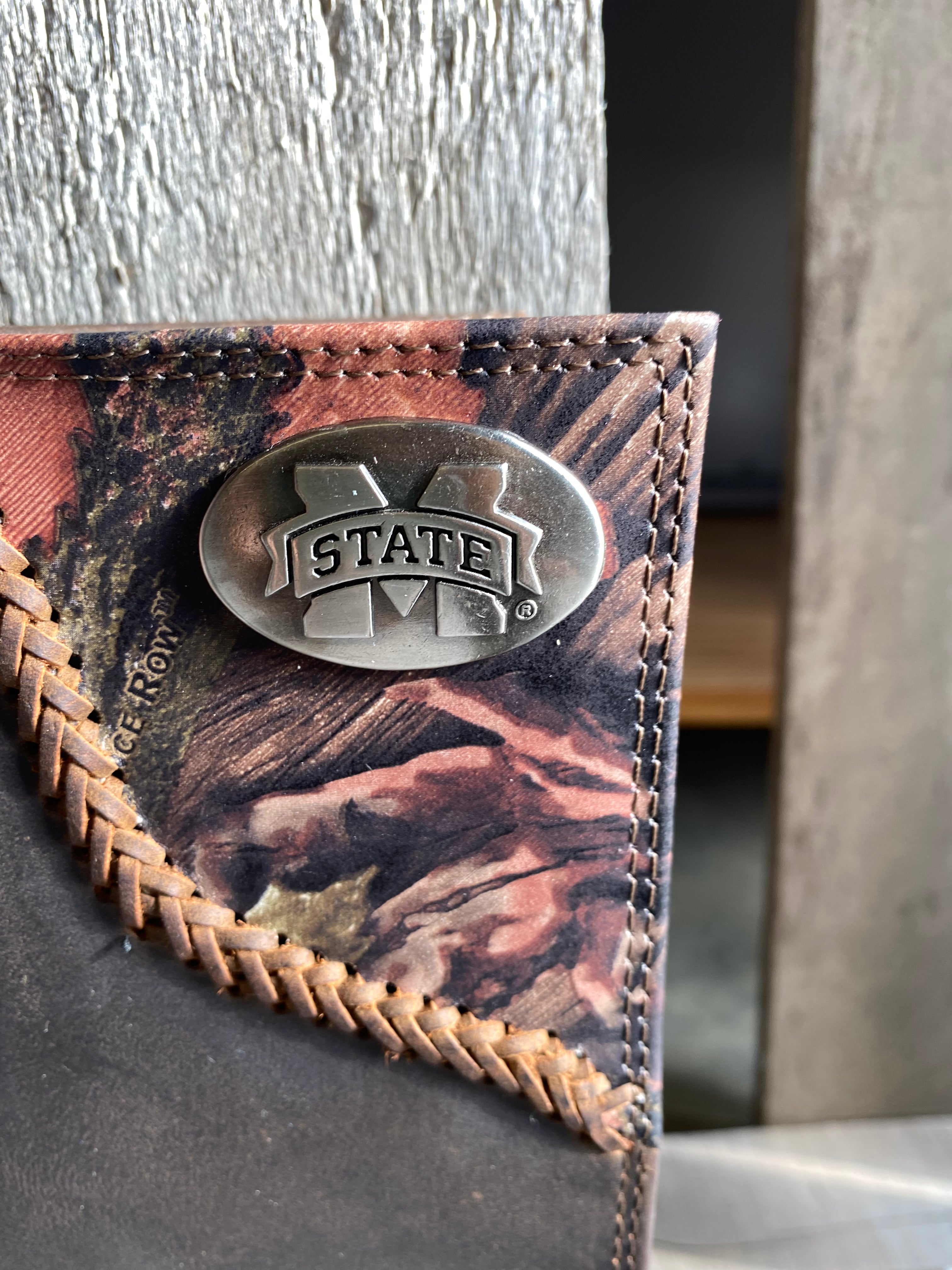 Zep-Pro MSU 1/2 Mossy Oak Camo/Brown Leather Bifold Wallet. Front view closeup of MSU "M State" brass concho on top right on camo leather.