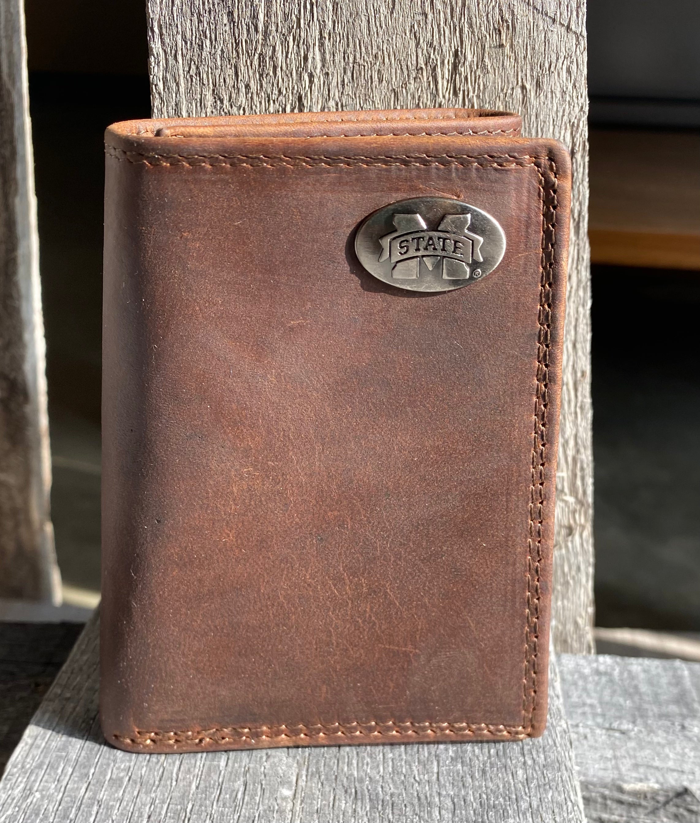 Zep-Pro brown "crazy horse" leather trifold wallet with a Mississippi State University Bulldogs "M State" brass concho on the top right.  Front view.