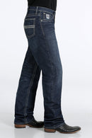 Side view of Cinch White Label dark wash jeans. Shows detail of right front coin and hip pockets, back pocket, and relaxed fit with stack on boots.